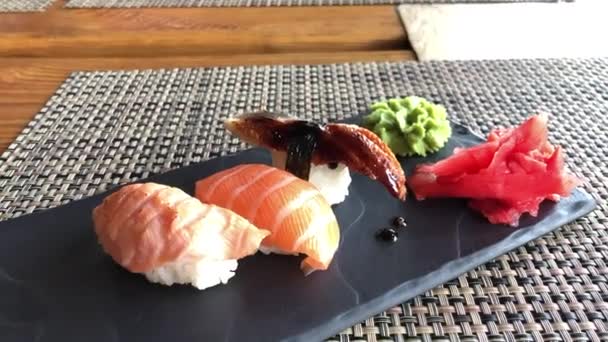 Tres tipos de sushi con pescado en una pizarra negra — Vídeo de stock