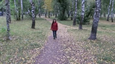 Sonbahar parkında sabah yürüyen genç bir kadın.