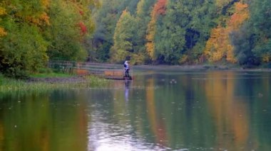 İnsanlar, ördekler ve renkli ağaçlarla sonbahar gölü manzarasının tadını çıkarıyorlar.