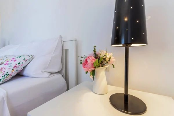 modern bedroom decoration with lamp and flowers on night stand