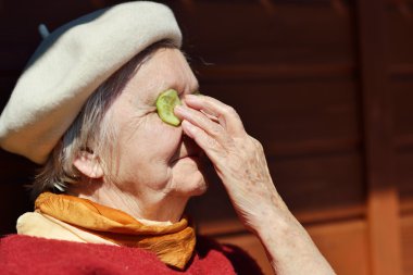 Yaşlı kadın salatalık gözünü koyarak