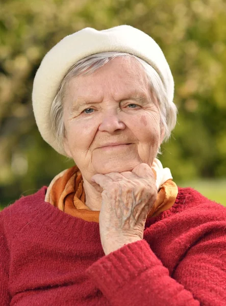 Senior woman smiling and dreaming in garden — Stock Photo, Image