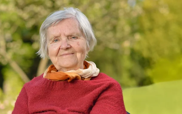 Senior vrouw glimlachend en dromen in tuin — Stockfoto