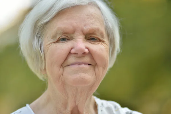 Старшая женщина улыбается в парке — стоковое фото