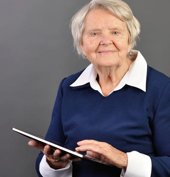 Senior šťastná žena s tablet proti šedé pozadí. — Stock fotografie