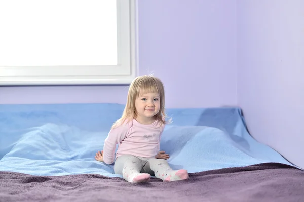 Menina sentada na cama no quarto . — Fotografia de Stock