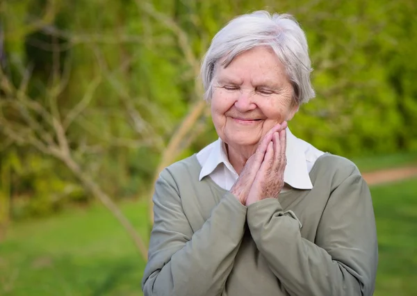 Glückliche Seniorin lächelt im Garten. — Stockfoto