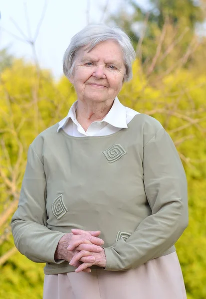 Senior woman looking and smiling in garden — Stock Photo, Image