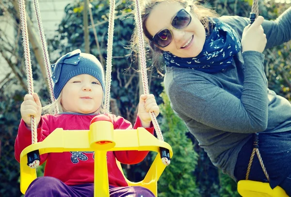 Mom playing with her daughter on a swing — Stock Photo, Image