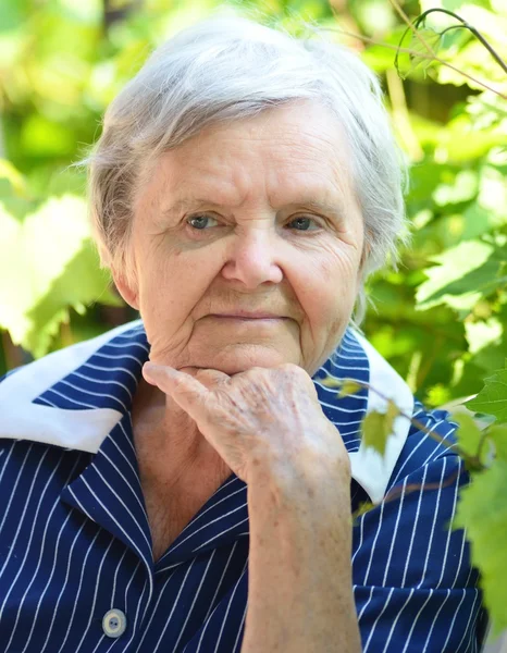 Femme âgée souriant et rêvant dans le jardin . — Photo