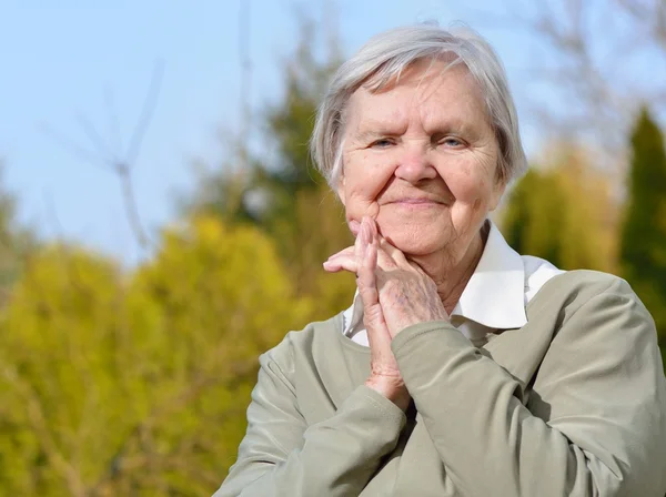 Seniorin schaut und lächelt im Garten — Stockfoto