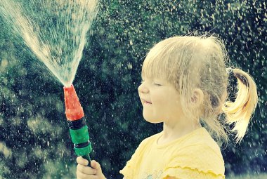 girl playing in the garden with hose