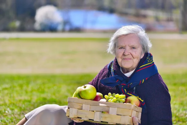 Senior woman in park with apples — Stock Photo, Image