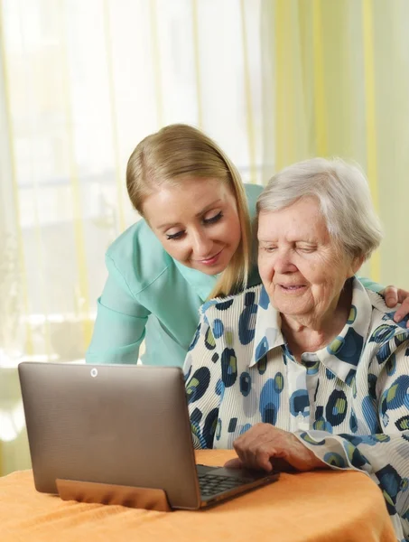 Senior woman with her caregiver using laptop — Stok fotoğraf