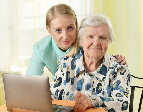 Senior woman with her caregiver using laptop — 图库照片