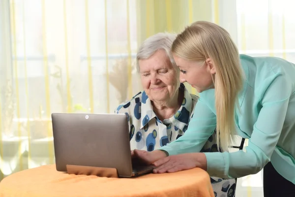 Senior woman with her caregiver using laptop — Stok fotoğraf