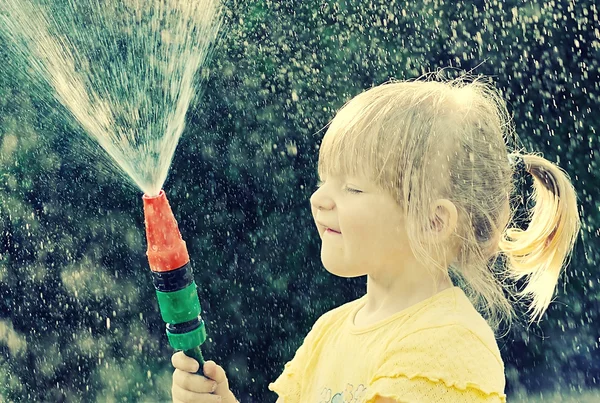 Girl playing in the garden with hose — Stok fotoğraf