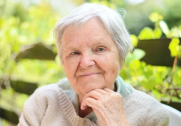 Senior woman dreaming in garden — Stock Photo, Image