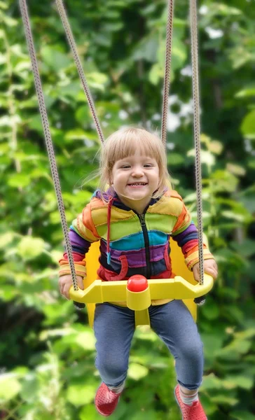 Linda niña balanceándose en columpios —  Fotos de Stock