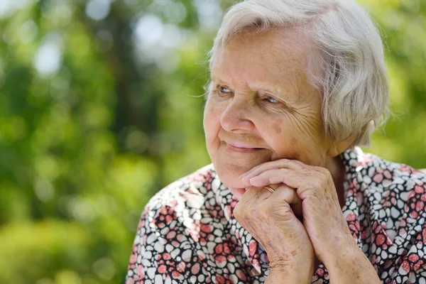 Seniorin träumt im Garten — Stockfoto