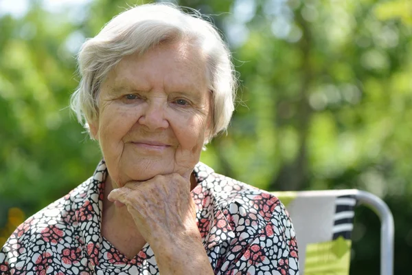 Senior woman dreaming in garden — Stock Photo, Image