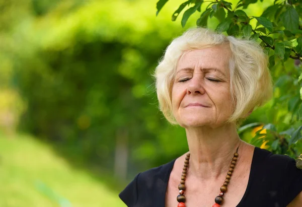 Reife blonde Frau im Garten lizenzfreie Stockbilder