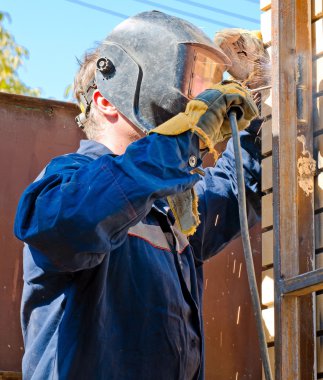 Kaynakçı maskeli mavi gökyüzüne karşı operasyon sırasında