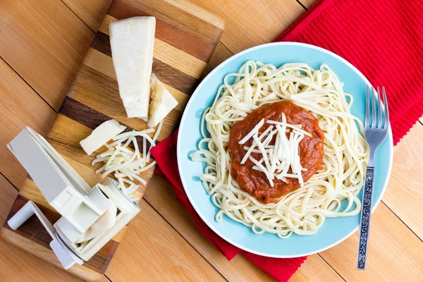 Сыр Gruyere и спагетти рядом с прессом для пасты — стоковое фото