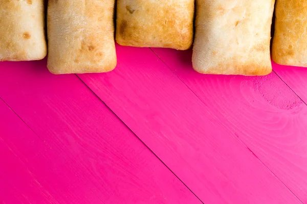 Fronteira de pão ciabatta italiano em rosa exótico — Fotografia de Stock