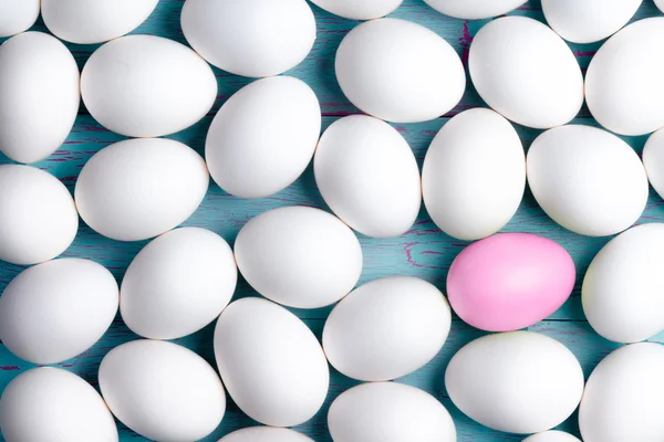 Большое количество белых пасхальных яиц и одно розовое — стоковое фото