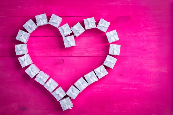 Gift boxes arranged as a heart on exotic pink — Stock Photo, Image