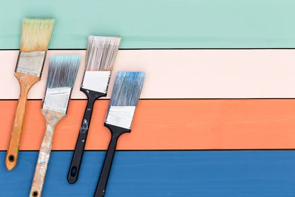 Quatro pincéis sobre superfície de madeira pintada — Fotografia de Stock
