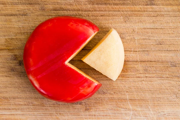 Wheel of fresh gouda cheese with a red rind — Stock Photo, Image