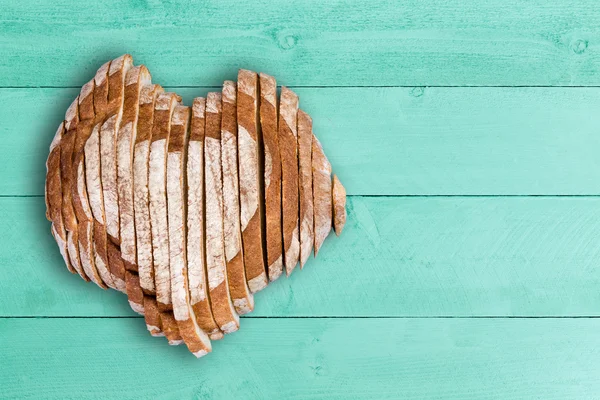 Sliced bread loaf shaped as heart over green wood — Stock Photo, Image