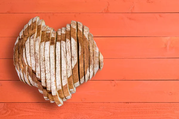 Lekker brood als hart gevormde over oranje lambrisering — Stockfoto
