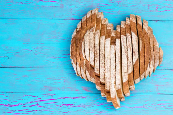 Plátky chleba ve tvaru srdce na starý modrý stůl — Stock fotografie