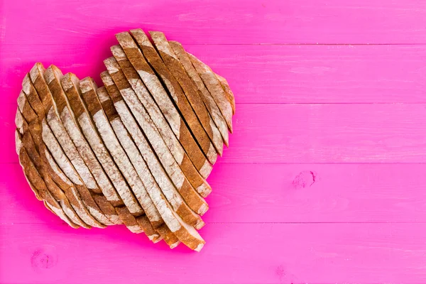 Krojonego chleba na różowym tle w kształcie serca — Zdjęcie stockowe