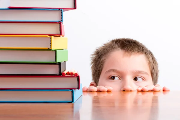 Thoughtful young schoolboy eyeing up his books — Stock Photo, Image