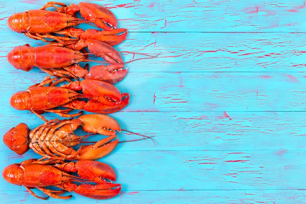 Colorful red lobster border on blue wood — Stock Photo, Image