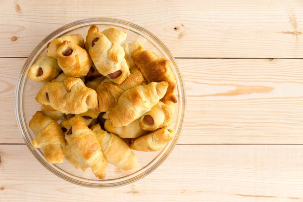 Glass plate heaped with fresh hot dog croissants — Stock Photo, Image