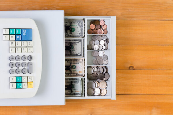 Выше вид на кассовый аппарат, полный монет
