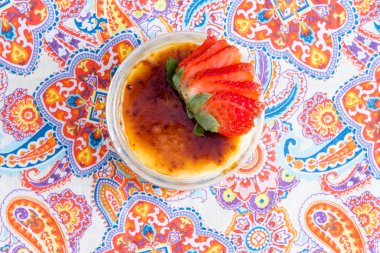 Yummy bowl of creme brulee with fresh strawberries clipart