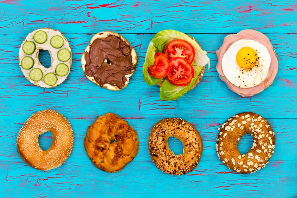 Four fresh sliced bagels with assorted filling — Stock Photo, Image