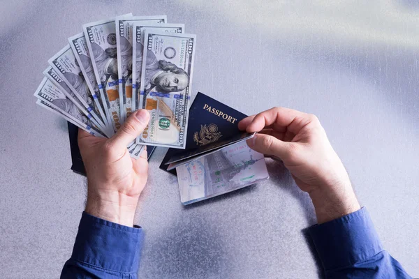 Facturas conceptuales de mano en dólares y pasaporte — Foto de Stock