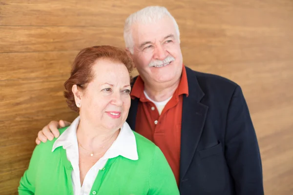 Heureux couple à la retraite sur fond de mur en bois — Photo