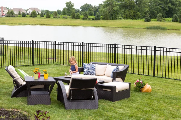 Little girl standing amongst garden furniture — Stock Photo, Image