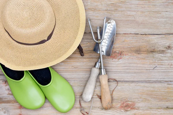 Шляпа, садовая обувь и инструменты на фоне дерева — стоковое фото