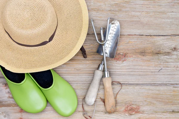 Sombrero, zapatos de jardinería y herramientas sobre fondo de madera — Foto de Stock