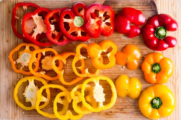 In Scheiben geschnittene rote und gelbe Paprika auf Holzbrett — Stockfoto