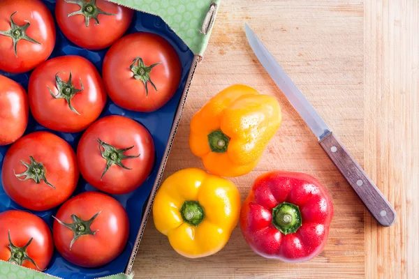 Tomates et poivrons sur le dessus de la planche à découper — Photo